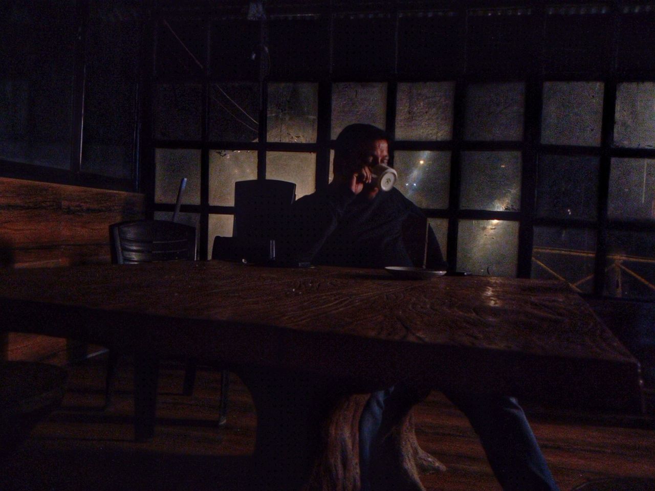 one person, adult, darkness, sitting, indoors, men, stage, table, screenshot, furniture, young adult, dark, night, person, waist up