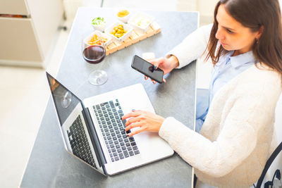 High angle view of woman using laptop on table at home