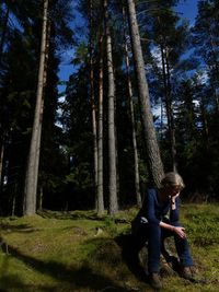 Woman sitting on tree trunk in forest