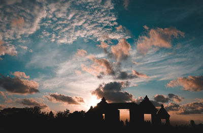 Silhouette houses against sky during sunset