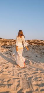 Rear view of woman on beach against clear sky