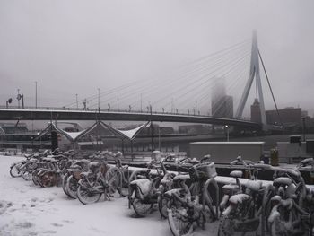 Bicycles by suspension bridge against clear sky during winter