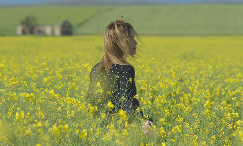 Rear view of woman amidst yellow flowers on field