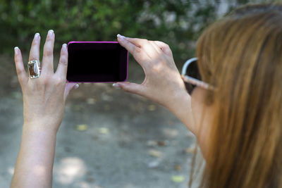 Midsection of woman photographing with mobile phone