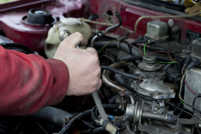 Cropped hand of mechanic repairing car engine car at garage