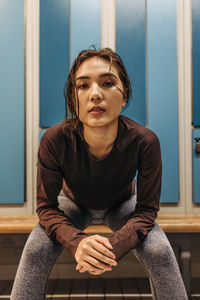 Portrait of confident female athlete sitting in locker room