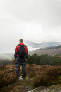 Rear view of hiker looking at mountain against sky