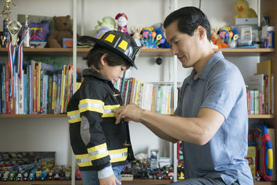 Father helping son in wearing costume at home