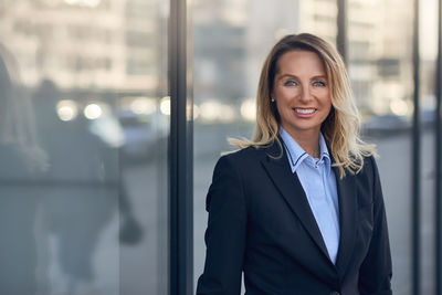 Portrait of smiling businesswoman against wall