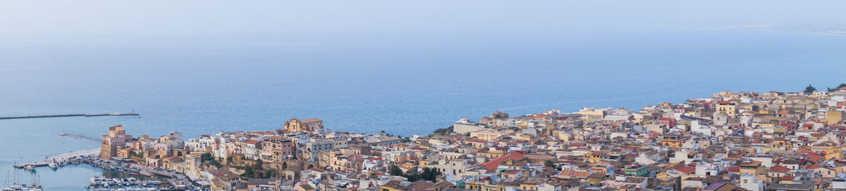 High angle view of townscape by sea against sky