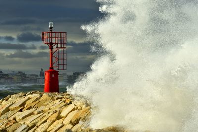 Lighthouse by sea against sky