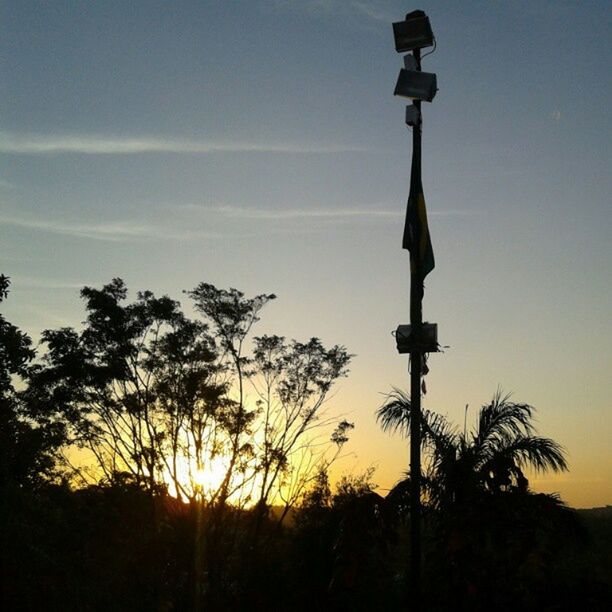 sunset, silhouette, sky, street light, tranquility, tree, tranquil scene, beauty in nature, scenics, nature, low angle view, sun, orange color, lighting equipment, idyllic, field, landscape, growth, outdoors, outline