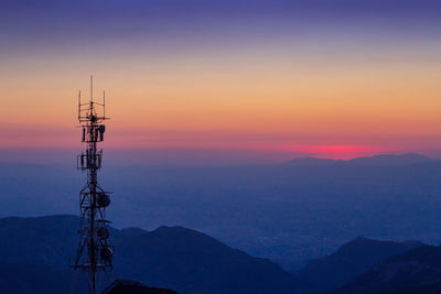 Silhouette communications tower against sky during sunset