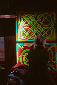 Rear view of woman standing against multi colored lights