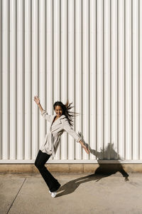 Carefree woman with arms outstretched dancing on footpath