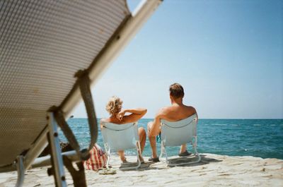 Rear view of women on beach against sky