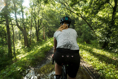 Rear view of woman cycling in forest