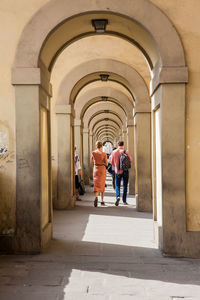 Rear view of people walking in corridor of building