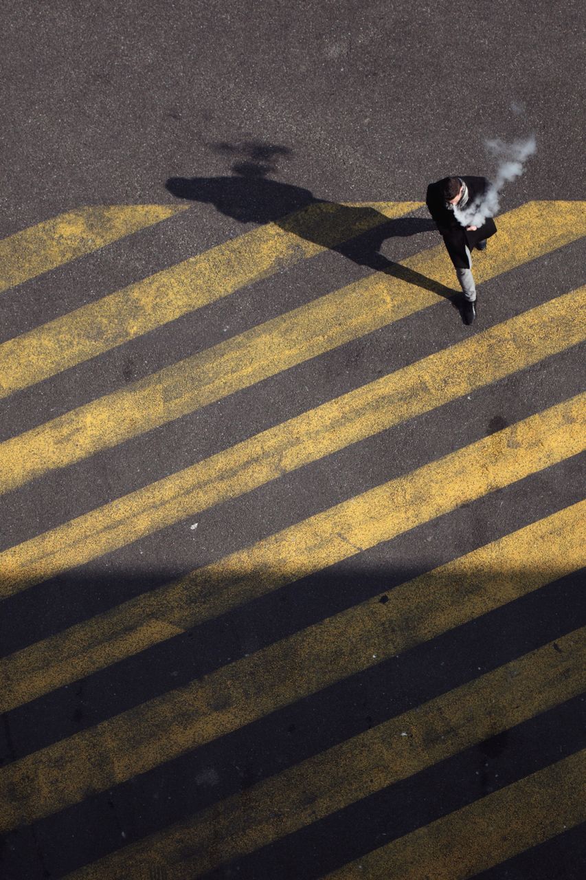 shadow, one person, full length, road, city, nature, sunlight, transportation, street, sign, motion, high angle view, day, road marking, yellow, outdoors, real people, adult, lifestyles, focus on shadow