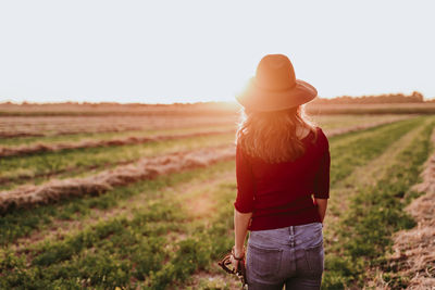 Rear view of woman standing on landscape during sunset