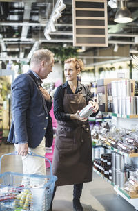Saleswoman explaining product to mature man in organic supermarket