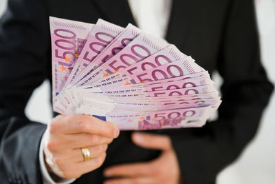 Midsection of businessman holding paper currency