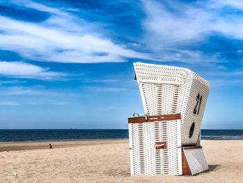 Hooded chairs on beach against sky