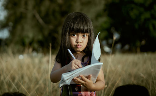 Portrait of elementary girl studying on field