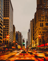 View of city street moving cars and buildings against sky