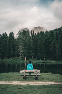 Man working in lake by trees against sky