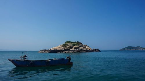 Sailboat in sea against clear blue sky