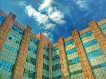 Low angle view of office building against cloudy sky