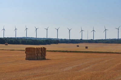 Wind turbines on field against clear sky