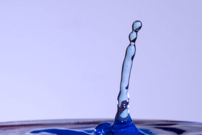 Close-up of water drop against blue sky