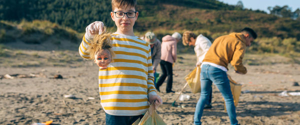 Portrait of boy holding garbage while standing at beach