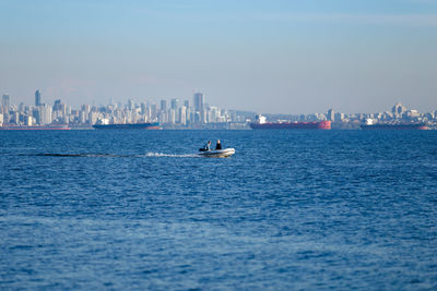 Boats sailing in sea against buildings in city