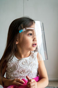 A toddler girl wearing the face protection shield. a safety corona mask during covid-19 pandemic.