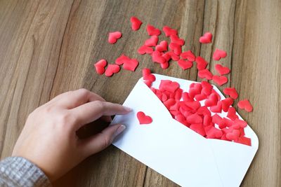 Cropped hand holding heart shape decoration on envelope