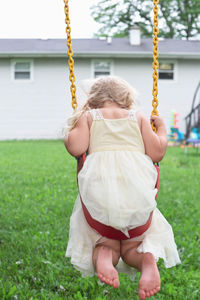Rear view of girl on swing at playground