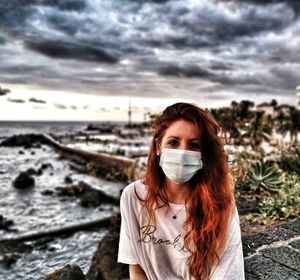 Portrait of young woman standing on land against sky