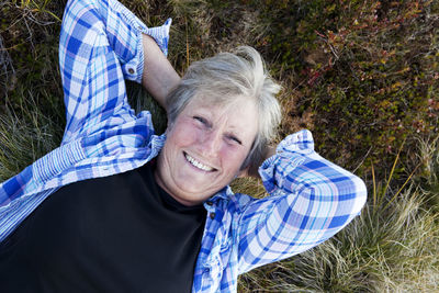 Smiling senior woman lying on grass