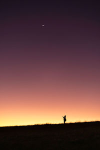 Silhouette person standing on field against sky during sunset