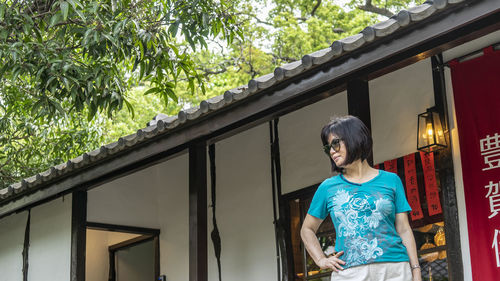 Woman standing by railing against window