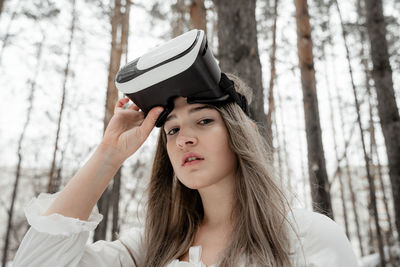 Woman wearing virtual reality simulator against trees outdoors