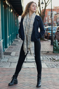 Portrait of young woman standing on footpath