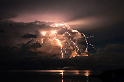 Firework display over lake against sky at night