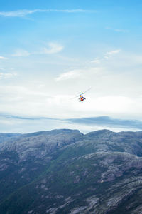 Low angle view of helicopter flying above mountains