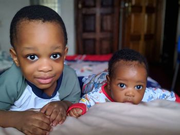 Portrait of cute siblings on bed at home