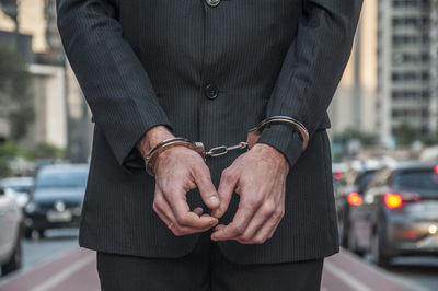 Midsection of businessman wearing handcuff on street in city