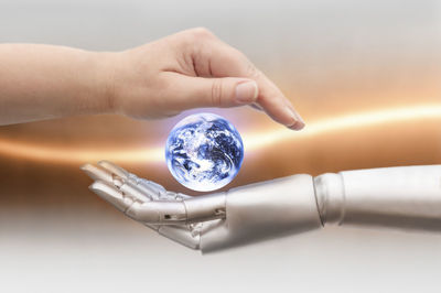 Close-up of robot and human hands covering globe